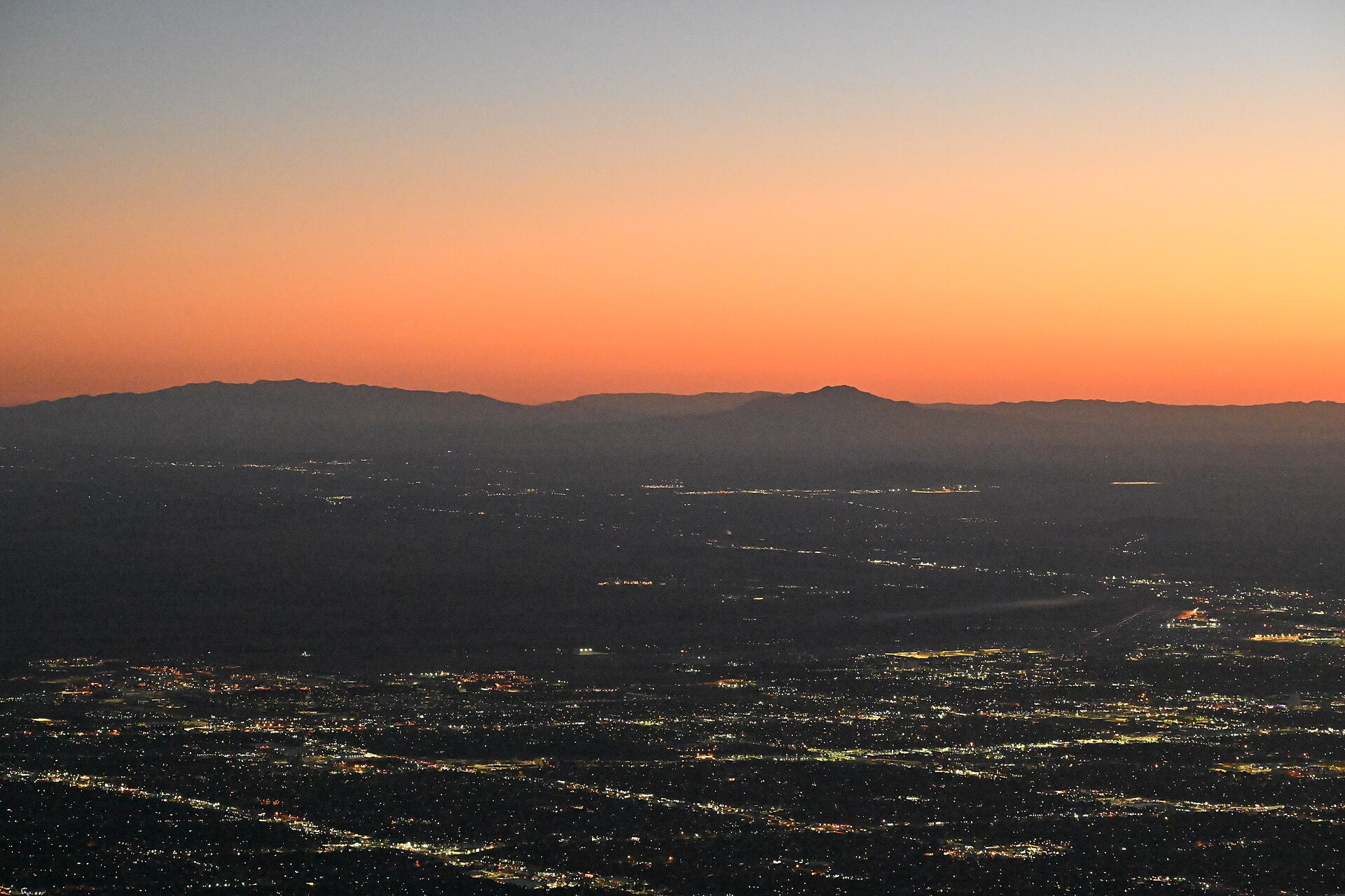 Real 2023 sunset over Albuquerque, New Mexico, with city lights and mountain silhouettes, photographed from Sandia Peak