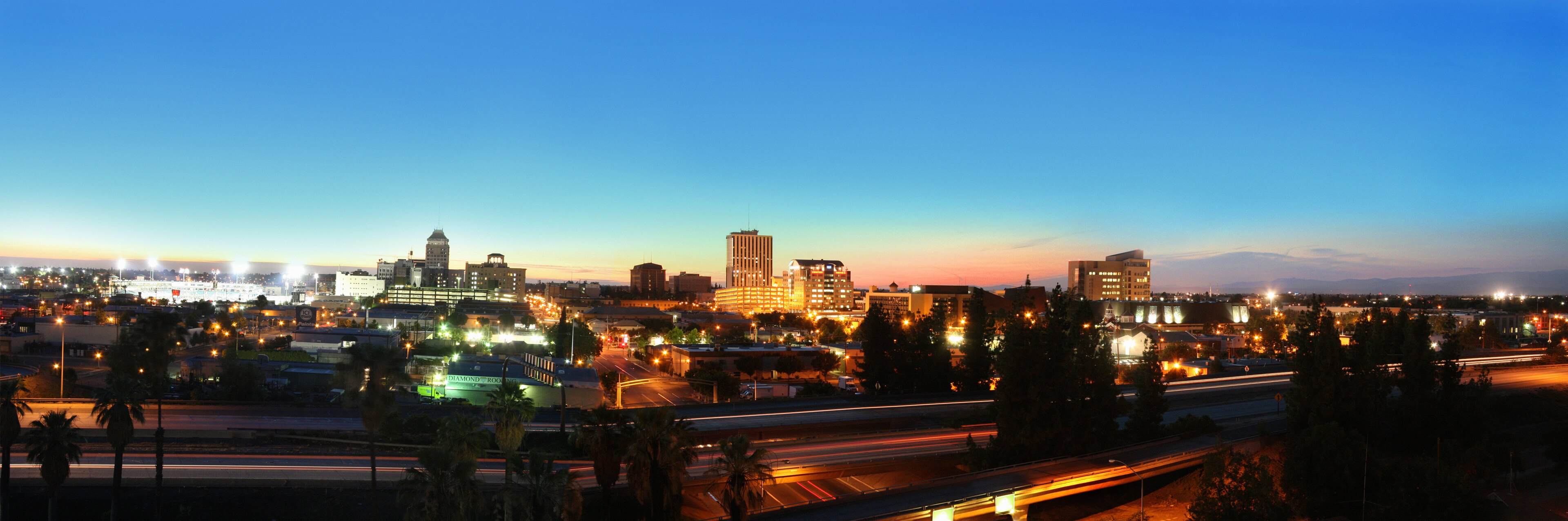Real downtown Fresno, California skyline at blue hour, with glowing city lights against a fading sunset sky