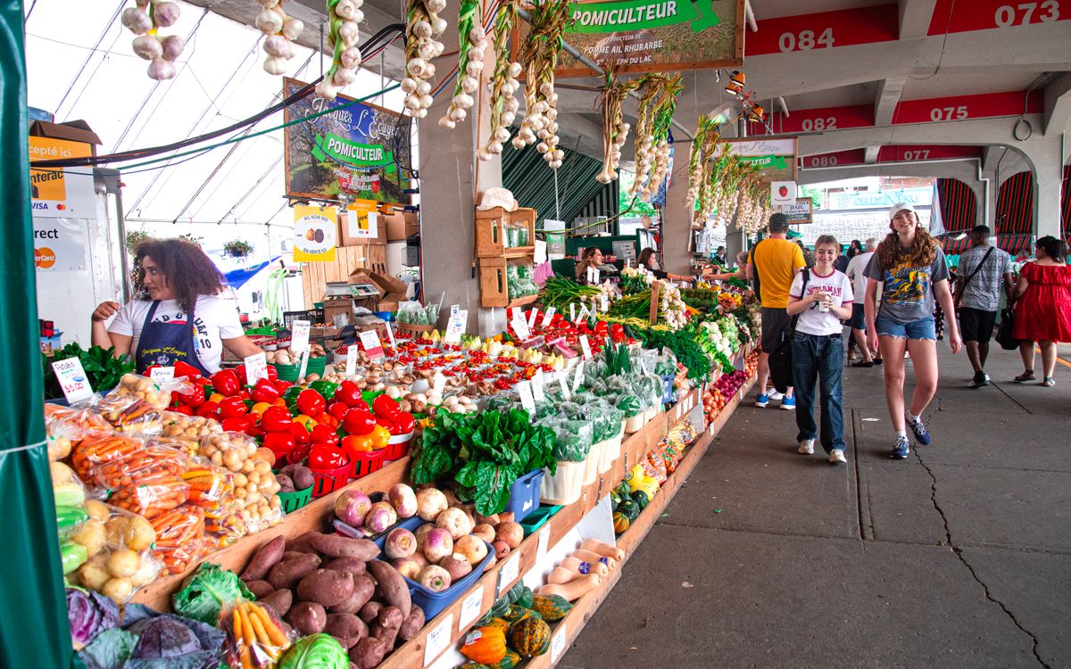 Illustrative photo of farmers market shoppers walking past colorful produce stalls; not the Florin Farmers Market
