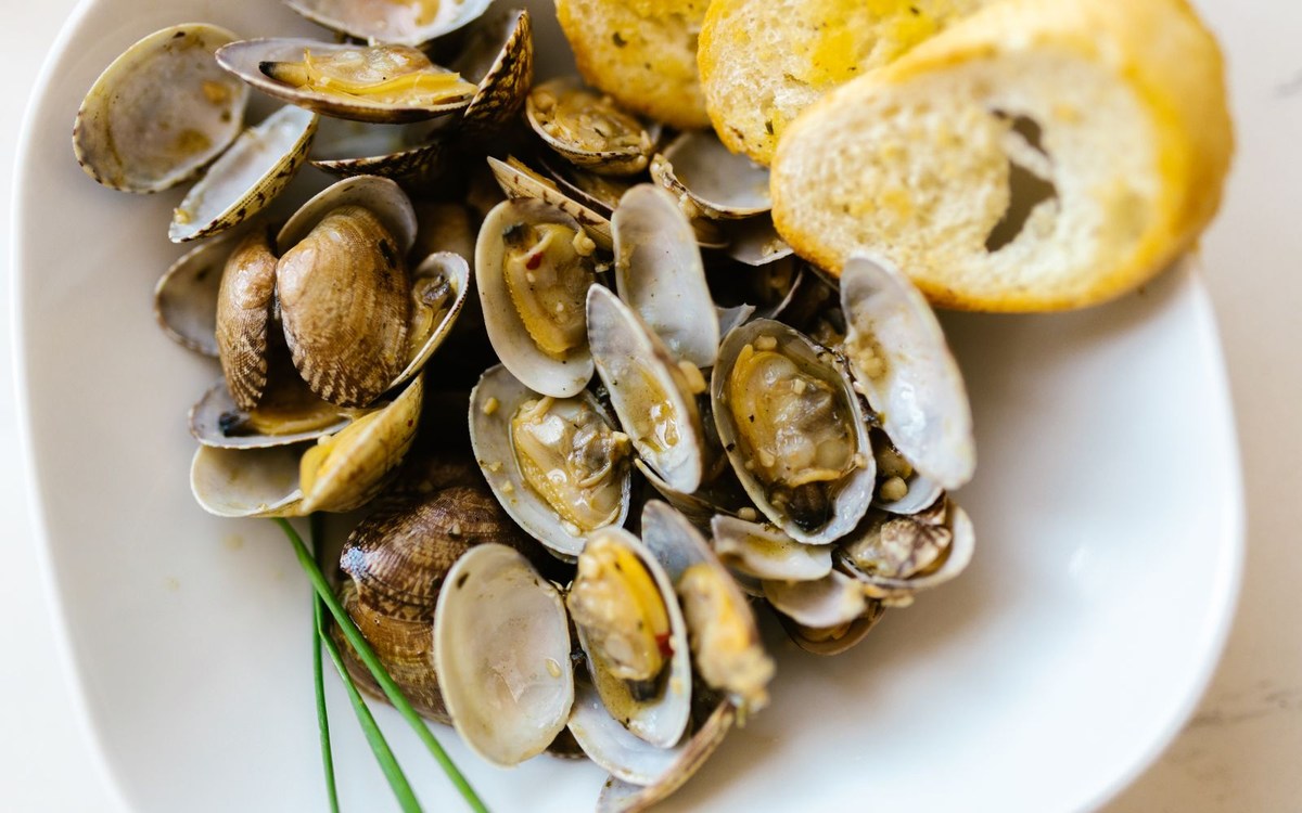 Illustrative photograph of steamed clams in broth with garlic bread; not a photograph taken at Remedy Kitchen & Tavern