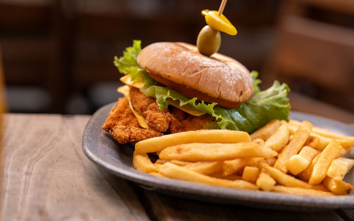 Illustrative photograph of crispy fried chicken sandwich with lettuce and fries; not a photograph taken at Heritage Bar & Kitchen