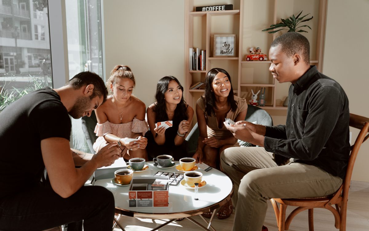 Illustrative photo of a group of friends playing a social tabletop game at a cafe, not at this venue