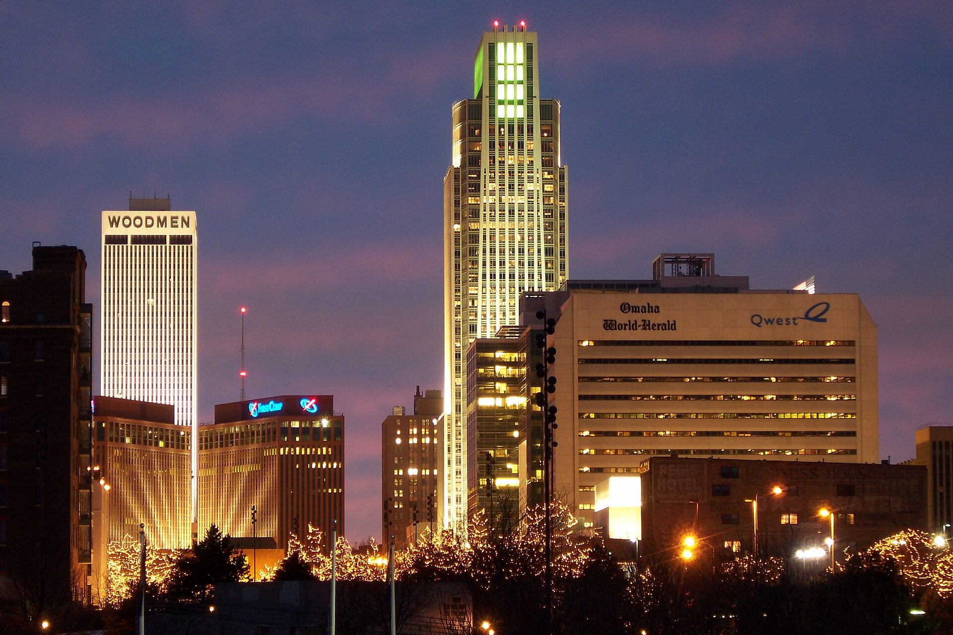 Real nighttime photograph of downtown Omaha, Nebraska, illuminated beneath a purple evening sky