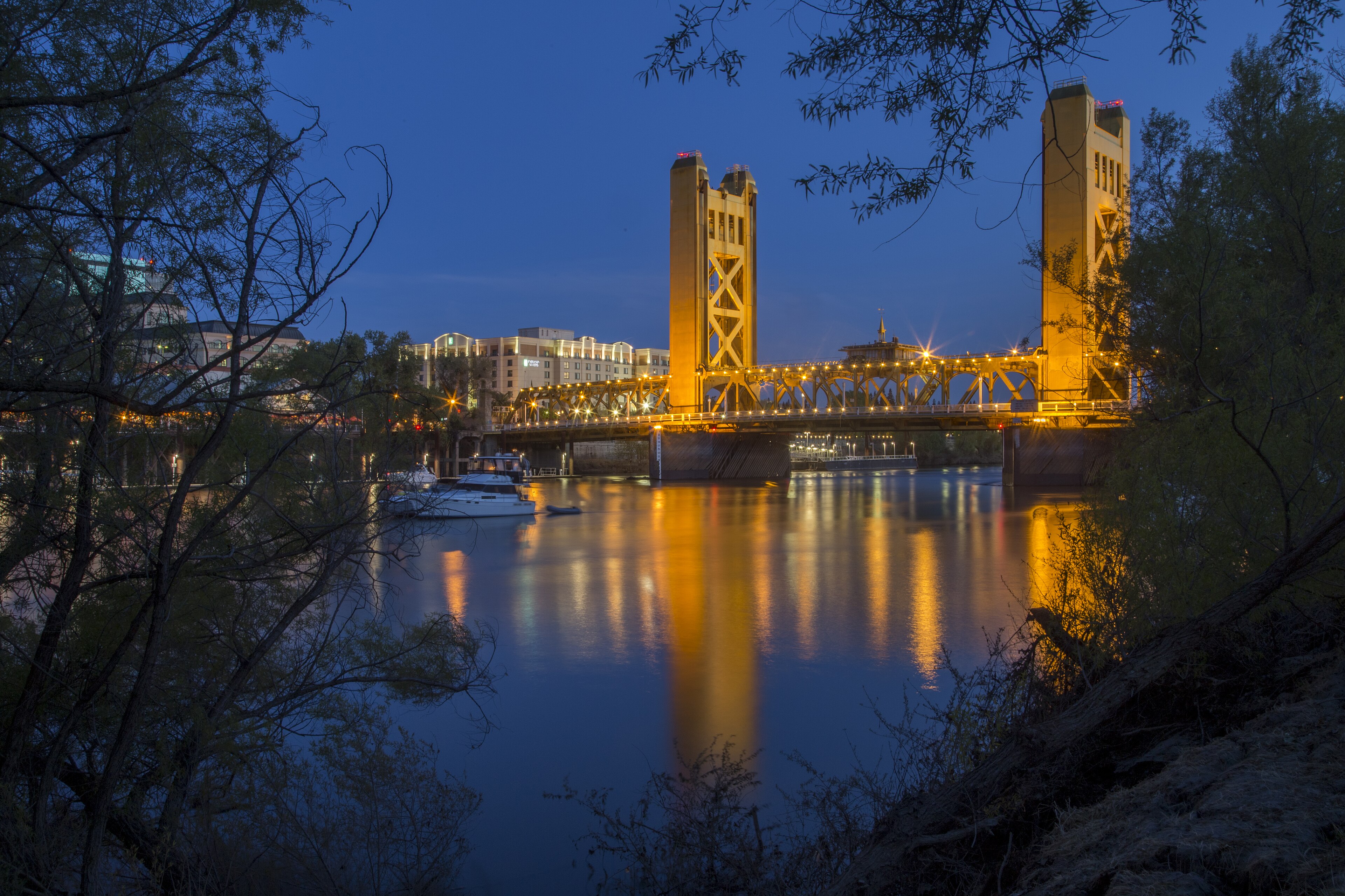 Real nighttime photograph of the illuminated Sacramento Tower Bridge and reflections in the Sacramento River