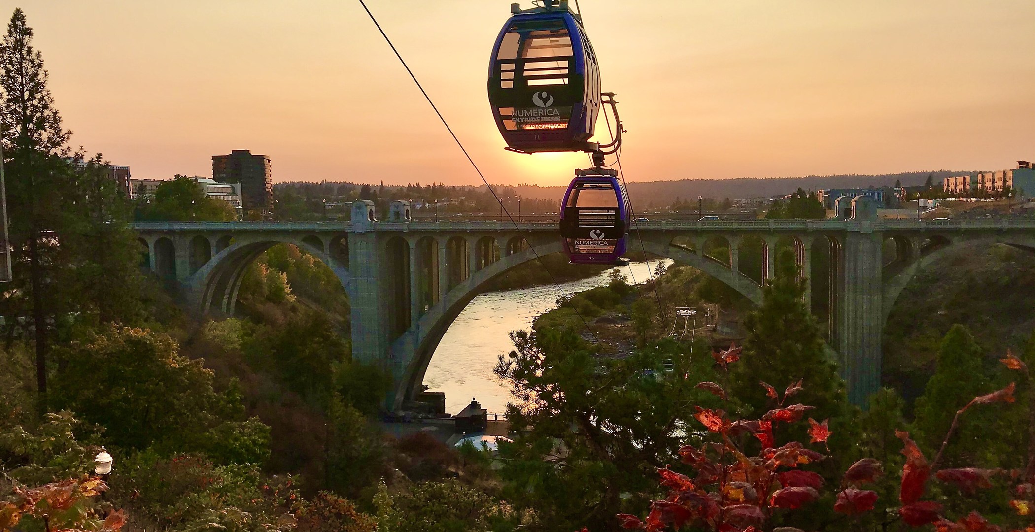 Real Spokane, Washington sunset over the Monroe Street Bridge and river, with the iconic skyride gondolas silhouetted against golden evening light